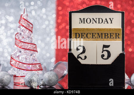 Ornements de Noël Calendrier en bois et l'arbre de Noël réflexion sur table en verre rouge sur un fond argenté Banque D'Images