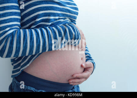 Pregnant woman touching et frottant son ventre, mère de caresser et de stimuler l'abdomen, des profils portrait féminin en cinquième mois ou vingt première semaine de Banque D'Images