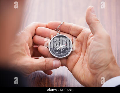 Close-up of hand holding compass sur fond blanc Banque D'Images