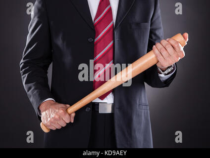 Close-up of Businessman Holding Baseball bat sur fond noir Banque D'Images