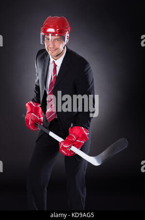 Portrait of a young businessman habillé en joueur de hockey sur fond noir Banque D'Images