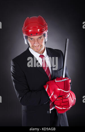 Portrait of a young businessman habillé en joueur de hockey sur fond noir Banque D'Images