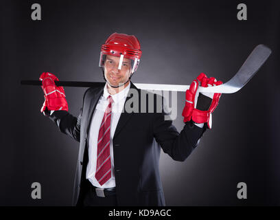 Portrait of a young businessman habillé en joueur de hockey sur fond noir Banque D'Images