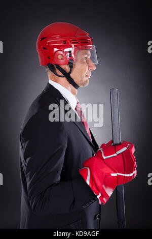 Portrait of a young businessman habillé en joueur de hockey sur fond noir Banque D'Images