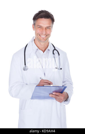Portrait of mature male doctor writing on clipboard sur fond blanc Banque D'Images