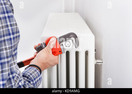 Close-up of Male Plombier radiateur fixation à l'aide d'une clé Banque D'Images