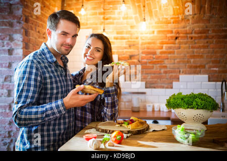 Young smiling couple manger des pizzas ensemble en cuisine Banque D'Images