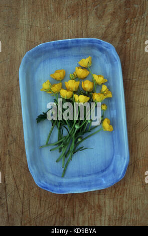 Bouquet de renoncules jaunes se trouvant en bleu plat sur table en bois Banque D'Images