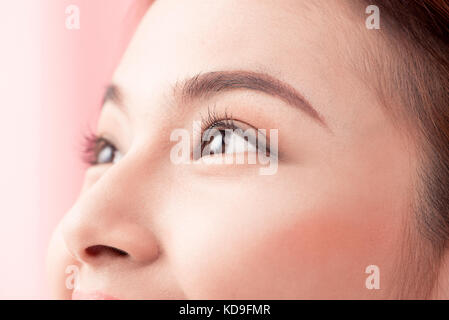 Belle femme asiatique yeux avec de longs cils isolé sur fond rose. Banque D'Images