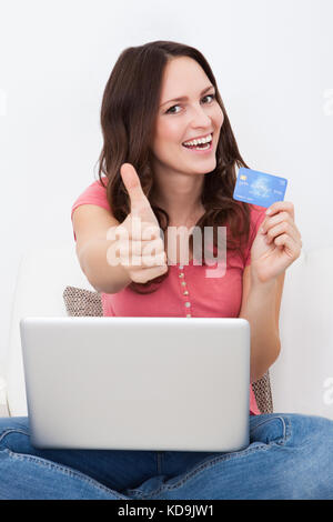 Young woman shopping online sitting on a couch Banque D'Images