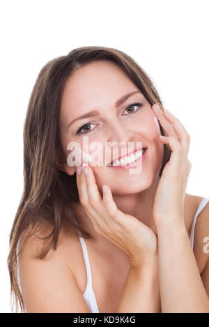 Happy Young Woman Applying Moisturizer Cream sur le visage Banque D'Images