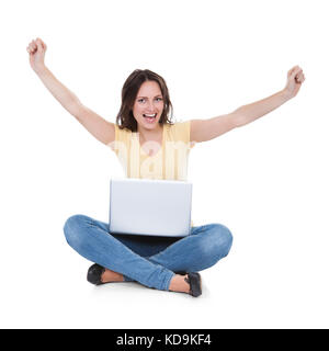 Jeune femme excité avec laptop Sitting on White Background Banque D'Images