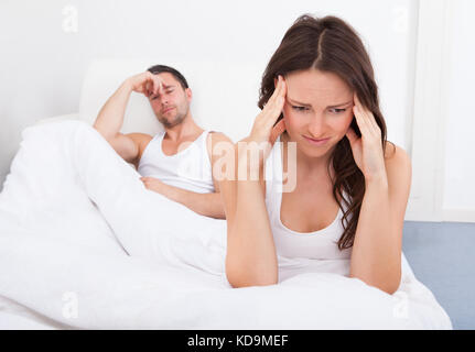 Frustrated Woman Sitting on Bed In front of Young Man Banque D'Images