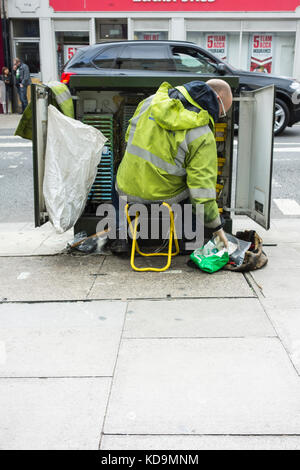 Un Ingénieur des télécoms BT Openreach fil de cuivre de l'installation dans un cabinet de télécommunications Banque D'Images