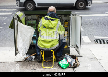 Un Ingénieur des télécoms BT Openreach fil de cuivre de l'installation dans un cabinet de télécommunications Banque D'Images