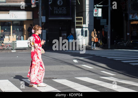 TOKYO - Japon - janvier 1, 2017. Une jeune fille portant un kimono est de traverser la rue dans le quartier d'Omotesando à Tokyo, Japon. Le kimono (着物, きもの Banque D'Images