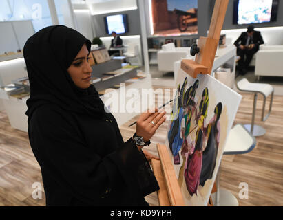 Francfort-sur-le-main, Allemagne. 11 octobre 2017. Une employée présente son art sur le stand Qatar à la Foire du livre de Francfort à Francfort-sur-le-main, Allemagne, le 11 octobre 2017. La plus grande foire du livre au monde se déroule jusqu'au 15 octobre. Crédit : Arne Dedert/dpa/Alamy Live News Banque D'Images