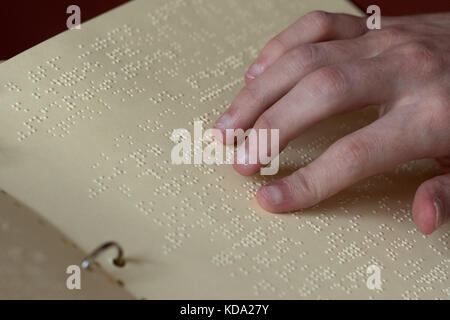 Le juge honoraire aveugle, Florian Schurbesmann, lisant un recueil de statuts en braille dans une salle d'audience de la Cour sociale de Ratisbonne, Allemagne, 11 octobre 2017. Photo: Armin Weigel/dpa Banque D'Images