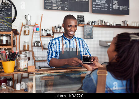 Smiling young barista café remise à un client cafe Banque D'Images