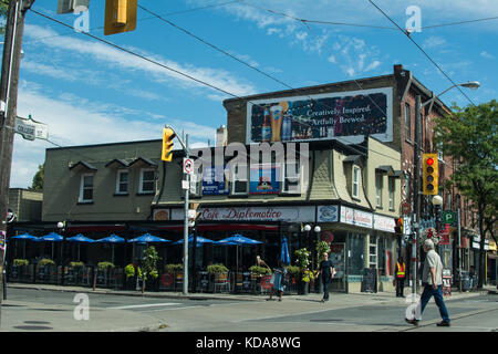 Enseigne de publicité de bière et Restaurant à Kensington place Toronto Canada homme traversant les câbles de la route câbles d'électricité parapluies signes d'usine de signe usines Banque D'Images