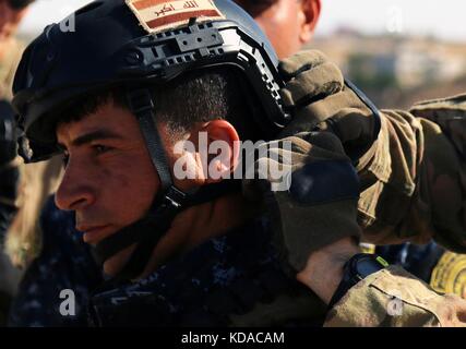 Un soldat américain permet d'ajuster le casque d'un policier fédéral irakien avant un cours de formation de sniper 16 mai 2017 près de Mossoul, en Irak. Banque D'Images