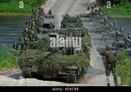 Des soldats américains, britanniques, lituaniens et polonais traversent un pont dans un convoi de véhicules de voie lors de l'exercice Saber Strike Exercise Iron Wolf le 20 juin 2017 à Rukla, en Lituanie. Banque D'Images