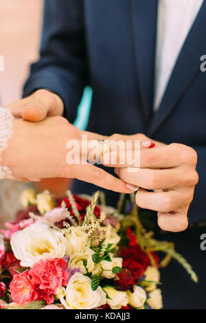 Vue rapprochée de la main du marié mettre la bague sur le doigt de l'épouse. Banque D'Images