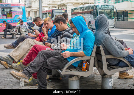 Les jeunes hommes travailleurs du bâtiment, portant des vêtements de travail, de prendre une pause et assis dehors sur un banc, à South Kensington, Londres, Angleterre, Royaume-Uni. Banque D'Images