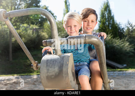 Deux garçons using digger sur terrain d'aventure dans la région de park Banque D'Images