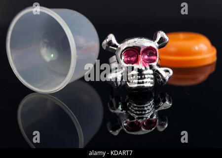 Close up of toy argent plastique bague tête de mort sur fond noir. machine gumball prix. Banque D'Images