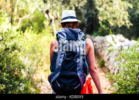 Sentier de randonnée femme on country rock avec clôture et bois. randonneur avec un chapeau est le trekking à travers la jungle de l'île sur terrain rugueux silba croatie. Banque D'Images