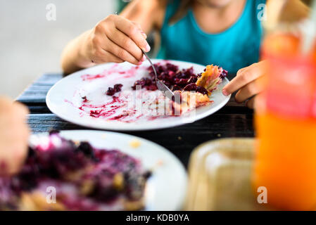 Les enfants mangeant avec strudel bleuet sucre sur le dessus. enfant mange de délicieuses pâtisseries est servi et mangé sur une plaque sur une table en bois dans les montagnes. Banque D'Images