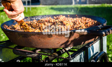 Cuisiner et préparer la Paella espagnole traditionnelle à carter en fonte de fer. la préparation de la paella en plein air sur la grande partie de la cour avant ou événement d'affaires. cate professionnels Banque D'Images