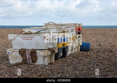 Les boîtes de poisson en plastique vides empilées sur une plage de galets Banque D'Images