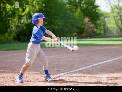 Garçon hitting ball tout en jouant au baseball dans un uniforme bleu Banque D'Images