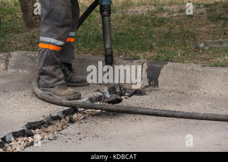 La réparation de la route fonctionne avec jackhammer. travailleur masculin à l'aide de marteau perforateur marteau pneumatique machines sur la réparation des routes. Banque D'Images