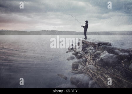 L'homme à un lac à la pêche dans la pluie Banque D'Images