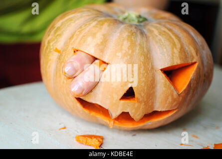 Processus de fabrication de jack-o-lanterne. image drôle de citrouille halloween monster face avec les doigts masculins. focus sélectif et flou. Banque D'Images