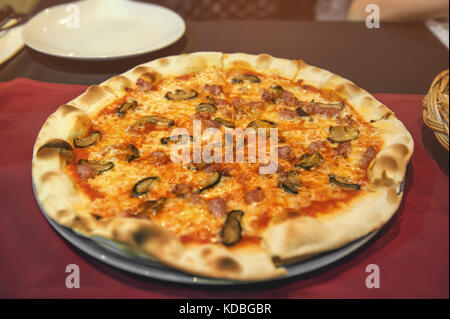 Saucisse ronde pizza Margherita sur une plaque blanche dans un café. Focus sélectif. La structure horizontale. Banque D'Images