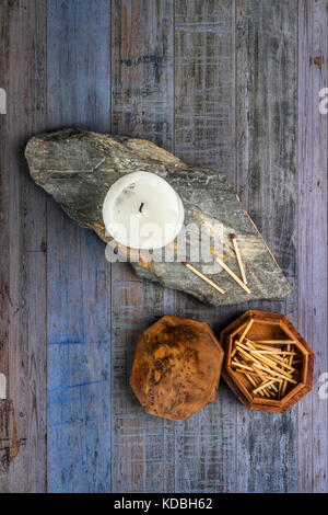 Cierge blanc sur un morceau d'ardoise avec une boîte en bois d'allumettes, sur une planche en bois historique Banque D'Images