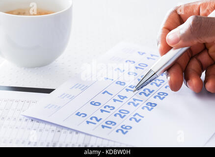 Close-up of man main tenir pen sur Calendrier Banque D'Images