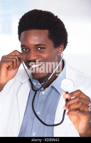 Portrait Of Happy Doctor with Stethoscope assis à un bureau Banque D'Images