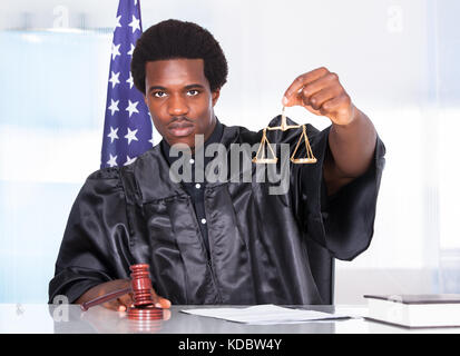 Portrait d'un juge africain Holding Gavel et l'échelle dans la salle d'audience Banque D'Images