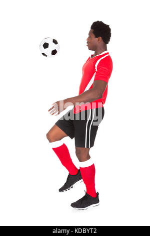 Portrait of African soccer player kicking football sur fond blanc Banque D'Images