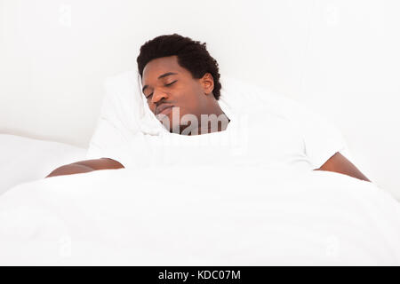 Beau Jeune homme africain Sleeping In Bed At Home Banque D'Images