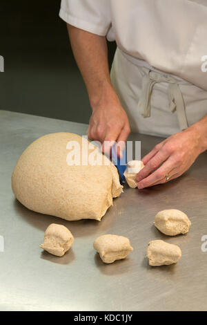 Fabrication de pain - coupe de pâte pour faire de petits pains dans une boulangerie, Royaume-Uni Banque D'Images