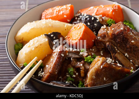 Côtes épicées à l'étuvée avec les champignons, les poires et les carottes close-up dans un bol. horizontale. korean style Banque D'Images