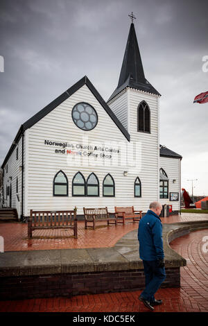 Un homme passe devant l'église norvégienne Seamens dans la baie de Cardiff, dans une matinée de printemps humide et froide, à Cardiff, au pays de Galles, au Royaume-Uni Banque D'Images