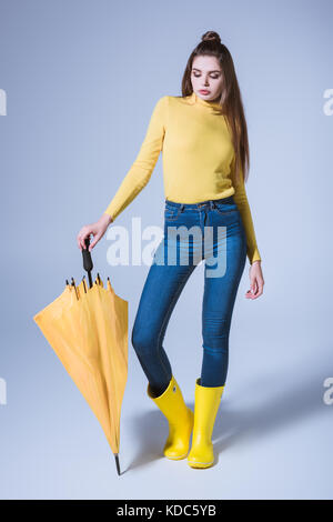 Fille en bottes de caoutchouc avec parapluie Banque D'Images