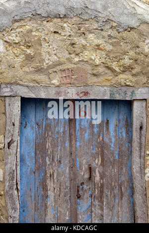 Une paire de portes en bois peintes en bleu pâle avec l'écaille de peinture situé dans un mur de pierre avec le nombre 61 soixante et un vissé sur la porte shabby chic. Banque D'Images